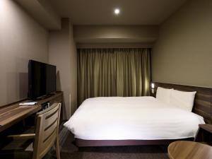 a hotel room with a bed and a desk with a television at Dormy Inn Premium Fukui Natural Hot Spring in Fukui +71 photos
