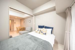 a bedroom with a large bed and a chair at Hie Apartment in Fukuoka