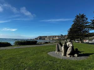 a statue of three people sitting on a grass field at Esplanade Stay in Kaikoura