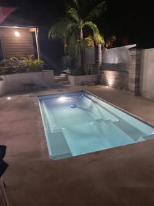 a swimming pool in a yard at night at O Coeur de l ouest bungalow Vanille Bourbon in Saint-Paul