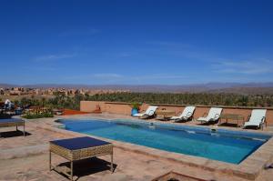 a pool with lounge chairs and a view of the desert at Auberge Kasbah Ennakhile in Nkob