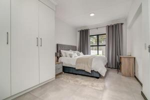 Schlafzimmer mit einem Bett mit weißen Wänden und einem Fenster in der Unterkunft Country Charm 2Bed 2Bath Fourways Sandton in Chartwell + 21 Fotos
