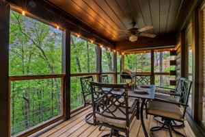 a screened in porch with a table and chairs at Mountain Majesty By Ghosal Luxury Lodging in Gatlinburg