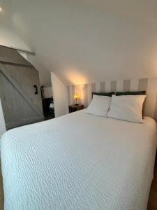 een slaapkamer met een groot bed met witte lakens bij Au bord de Mers in Mers-les-Bains