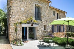 a patio with a table and an umbrella in front of a building at Le Mas du Four a Chaux in Gordes