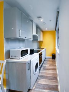 a kitchen with a washing machine and a microwave at Beachside Bliss in Bournemouth
