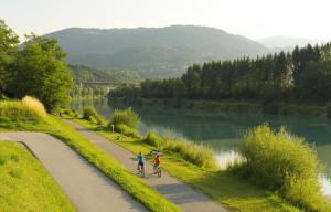 two people riding bikes on a path next to a river at Urlaubsapartment am Silbersee in Villach