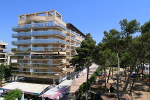 a tall apartment building with a parking lot and trees at Park Suites Family Rentalmar in Salou