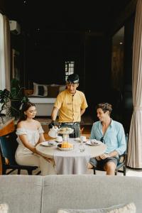 a group of people sitting at a table with a cake at Magical Jungle Resort in Ubud