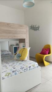 Un dormitorio con una cama y una silla amarilla. en AltamareA Vacation home, en Brucoli