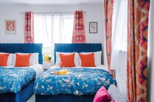 a bedroom with two beds with blue and orange pillows at Jephsons Lodge Studio 3 - Free Netflix, Parking, WiFi in Leamington Spa