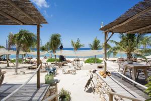 - une plage de sable avec des tables et des chaises dans l'établissement Tropical Stay at Puru Resort, à Willemstad