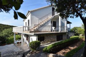 a white house with a balcony with a dog on it at Apartmani Marko in Gdinj