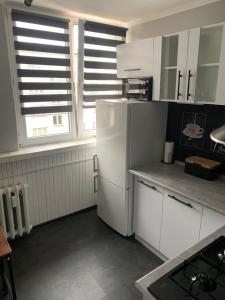 a kitchen with white cabinets and a refrigerator at Apartament na Jasnym in Dzierżoniów
