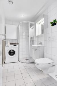 Un baño blanco con inodoro y lavadora. en Penthouse in Trondheim, Solsiden, en Trondheim