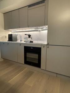 una cocina con armarios blancos y un aparato negro en Penthouse in Trondheim, Solsiden, en Trondheim