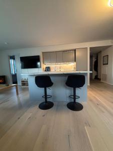 una cocina con dos taburetes negros en un mostrador en Penthouse in Trondheim, Solsiden, en Trondheim