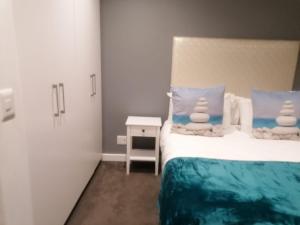 a bedroom with a bed with blue and white pillows at The Pearls or Oceans Umhlanga in Durban