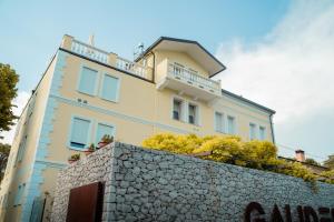 a yellow building with a stone wall at Locanda Gaudemus Boutique Hotel in Sistiana