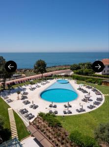 a large swimming pool with chaise lounge chairs and the ocean at Villa Galé Cascais in Cascais