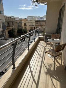 un balcon avec deux chaises et une table sur un immeuble dans l'établissement Swieqi sunny central airy quiet Apartment in Malta, à Is-Swieqi