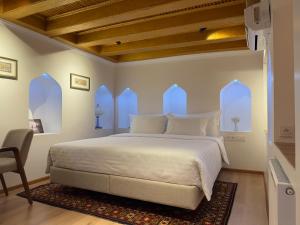 a bedroom with a large white bed with windows at Usman Heritage in Bukhara