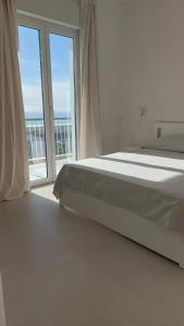 a white bedroom with a bed and a large window at Temples and Sea view Apartment in Agrigento