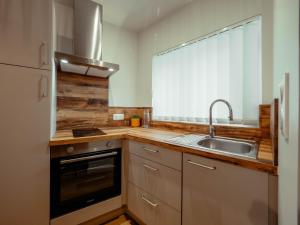 une petite cuisine avec un évier et une cuisinière dans l'établissement Appartement Cosy Cœur de la Normandie, à Creully