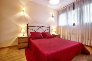 a bedroom with a red bed with two red pillows at Urbanización Barrio de Triana 3c in Nueva de Llanes