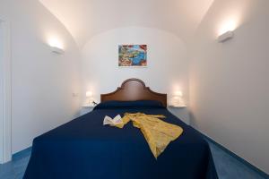 a bed with a blue blanket and a book on it at Secret Amalfi - Your stay in downtown Amalfi in Amalfi