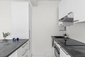 a kitchen with white cabinets and a stainless steel counter top at Scandinavian attic apartment in the city center in Helsinki +6 photos