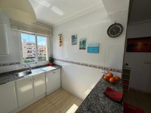 une cuisine avec un évier et une horloge murale dans l'établissement Apartamento VICTORIA Cabo Roig, à Orihuela Costa
