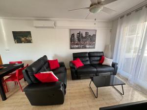 un salon avec des meubles en cuir noir et des coussins rouges dans l'établissement Apartamento VICTORIA Cabo Roig, à Orihuela Costa