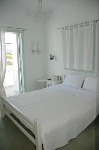 ein weißes Schlafzimmer mit einem großen Bett und einem Fenster in der Unterkunft Crisio Studios in Skyros + 31 Fotos