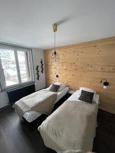 two beds in a room with a wooden wall at Lysgaard Cosy Cottage in La Bresse