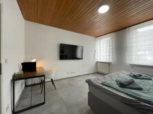 ein Schlafzimmer mit einem Bett, einem Schreibtisch und einem Fernseher in der Unterkunft Danisman Apartments 3 Zentral - Smart - Modern in Saarbrücken