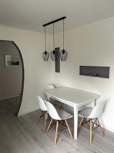 a dining room with a white table and chairs at Vivist apartments in Druskininkai