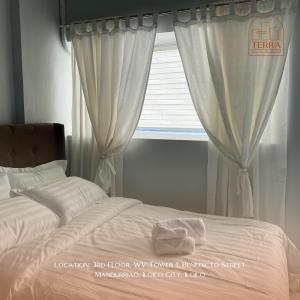una camera da letto con un letto e una finestra con tende di Terra Condo a Città di Iloilo Altre 9 foto