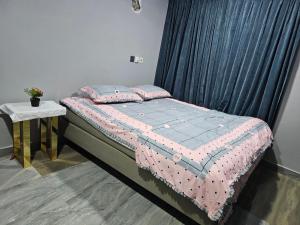 a bed with a pink and blue quilt and a table at Place with family in mind in Weija