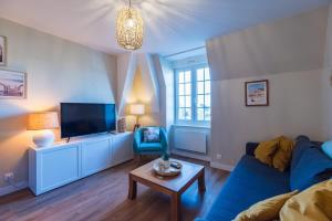 a living room with a blue couch and a tv at Escapade a Tregastel plages et commerces proches in Trégastel