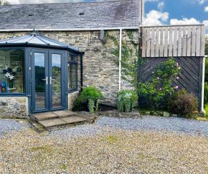 ein Cottage aus Stein mit einer Glastür davor in der Unterkunft Horseshoe Cottage Aberaeron in Ciliau-Aeron