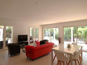 a living room with a red couch and a table at Villa familiale au Cap Ferret: face aux dunes, proche plage, grand jardin et terrasse, 10 pers - FR-1-736-8 in Lège-Cap-Ferret