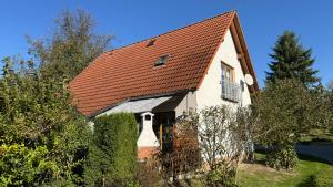 a white house with an orange roof at Ferienhaus RENA mit Pool in Bischdorf