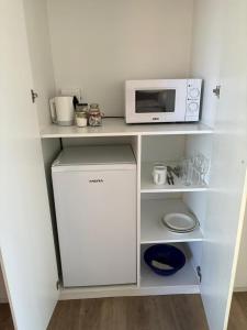 a small kitchen with a microwave and a refrigerator at Cozy en-suite room in Wellington with own entrance in Wellington