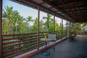 a balcony with a table and chairs and palm trees at Laoxao RiverStone Villa in Hoi An