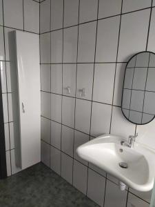 a white tiled bathroom with a sink and a mirror at Le bonheur pour tous - Gîte rural PMR en Ardennes in Tellin