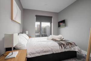 a white dog laying on a bed in a bedroom at Dockside Escape By Royal Albert Dock in Liverpool