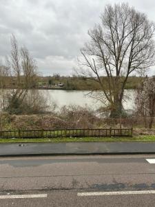 a road with a view of a river and a fence at Appartement bord de seine in Orival