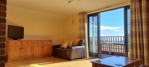 a living room with a chair and a tv and a balcony at The Dairy in Teignmouth