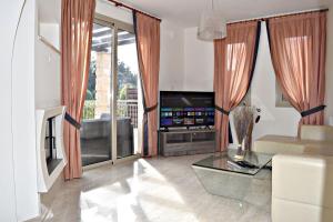 a living room with a couch and a tv at Villa Lalianda Sandy Beach Villas - Private Pool - Jacuzzi - Private Beach Area in Polis Chrysochous